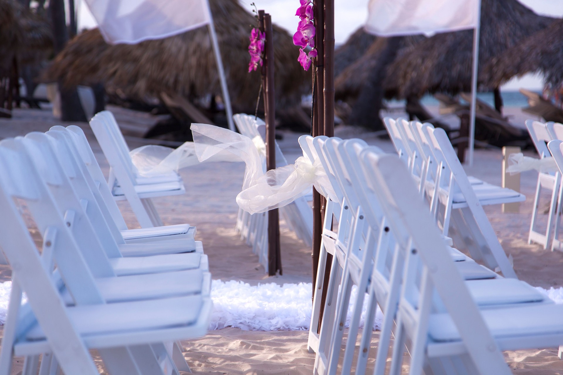 Elegant beach wedding ceremony setup with white chairs and floral decorations on the shore